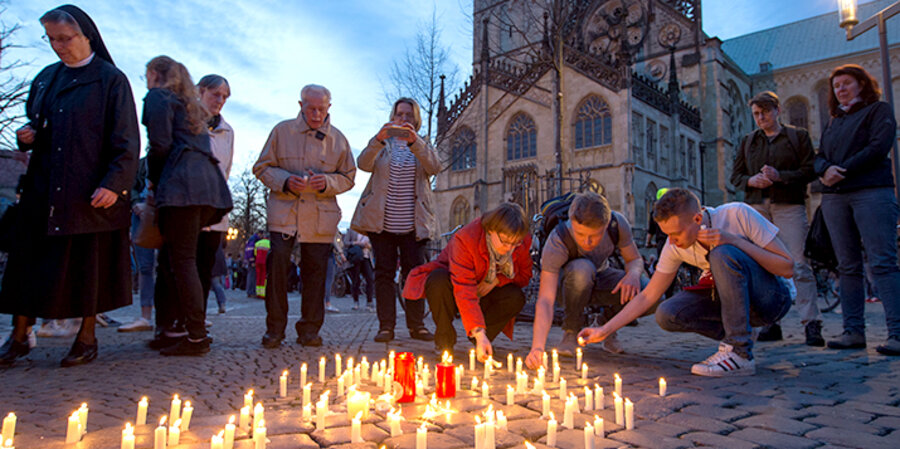 Menschen stellen nach dem Gedenkgottesdienst Kerzen vor dem Dom auf. Foto: picture-alliance/Friso Gentsch/dpa