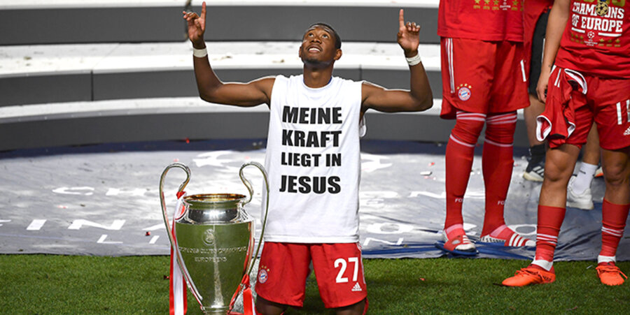 David Alaba kniet neben dem Siegerpokal der Fußball-Champions-League. Foto: imago-images