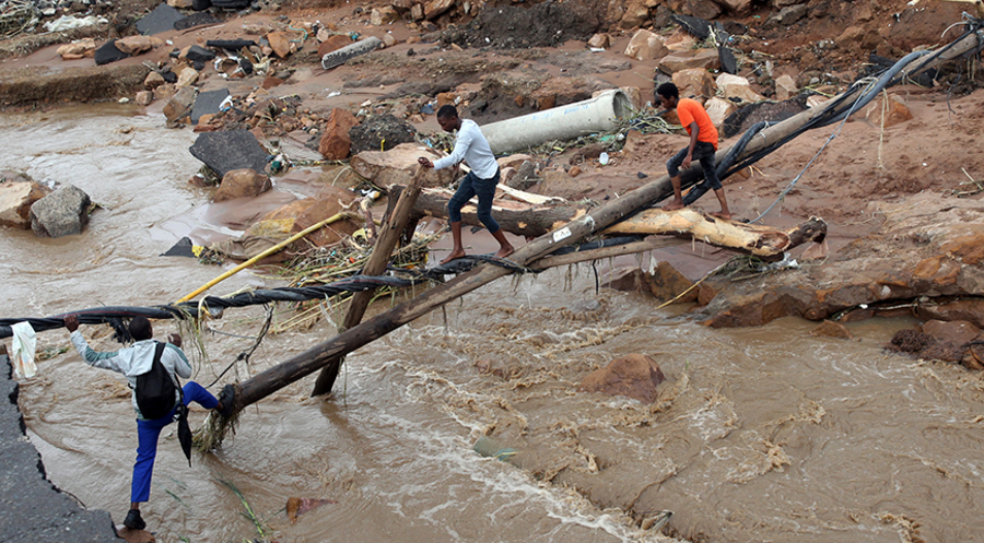 Die Männer bauen eine Brücke aus Baumstämmen. Foto: Picture Alliance/ASSOCIATED PRESS | STR