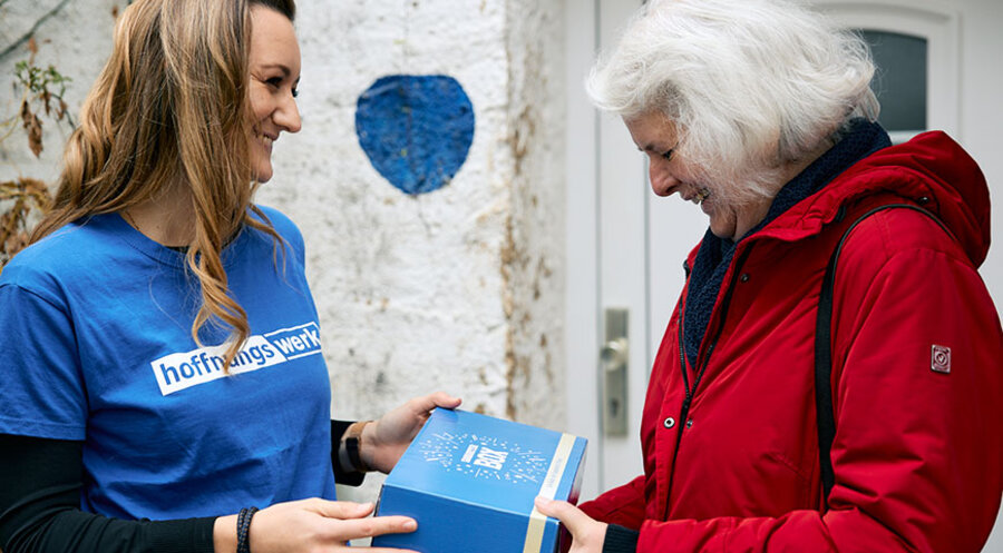 Eine Mitarbeiterin vom „Hoffnungswerk“ übergibt eine Samariterbox. Foto: creedoo/ Daniel Höly