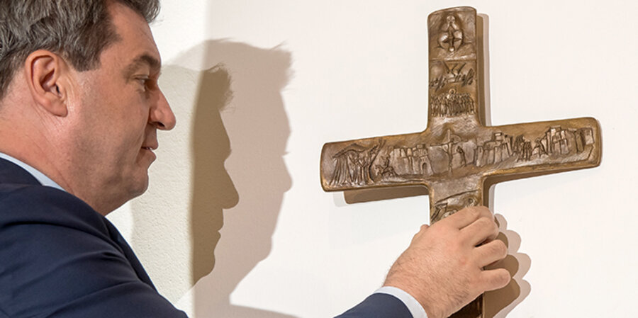 Ministerpräsident Markus Söder (CSU) hängt ein Kreuz im Eingangsbereich der bayerischen Staatskanzlei auf. Foto: picture-alliance/Peter Kneffel/dpa