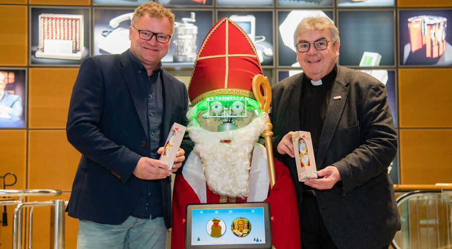 Mit dem Nikolaus-Roboter wollen HNF-Geschäftsführer Dr. Jochen Viehoff (links) und Bonifatiuswerk-Generalsekretär Monsignore Georg Austen Kindern eine kleine Freude machen und zugleich ein Zeichen für Nächstenliebe setzen. Foto: HNF/Sergei Magel