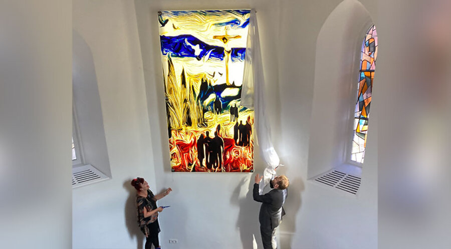 Glaskünstlerin Katrin Engel-Meyer von der Glasmalerei Sattler und Pfarrer Dirk Fiedler stehen vor dem neuen Kirchenfenster von Modeschöpfer Harald Glööckler. Foto: Christoph Zacheus-Hufeisen