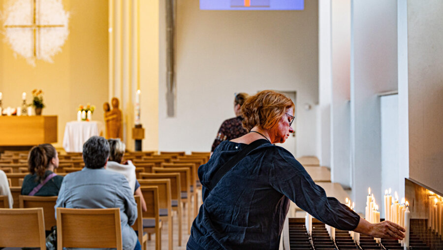 Teilnehmerin am Trauergottesdienst entzündet eine Kerze im Gedenken an die Opfer der Messerattacke am 23. August. Foto: picture alliance / epd-bild | Meike Böschemeyer