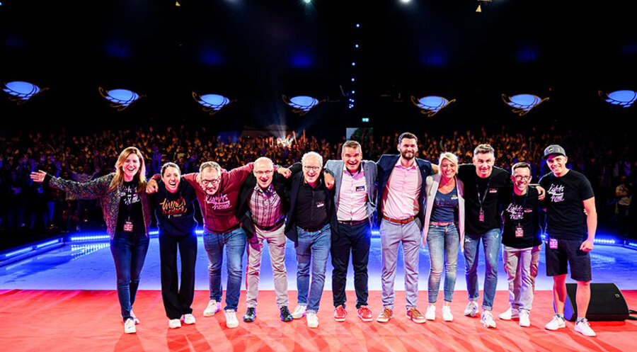 Der Vorstand und das Leitungsteam von „Weihnachten neu erleben” Im Hintergrund die 900 Mitwirkenden an der Kickoff-Veranstaltung. Foto: Weihnachten neu erleben e.V./Tobias Nikola