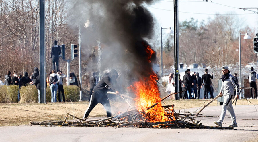 Menschen verbrennen Äste, um während eines Aufstands in Norrköping, Schweden, am 17. April 2022 eine Straße zu blockieren. Foto: picture alliance / TT NEWS AGENCY