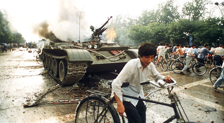 Das Archivbild vom 4.6.1989 zeigt Menschen neben einem in Brand gesetzten Panzer westlich des Tien An Men-Platzes (Platz des Himmlischen Friedens) in Peking. Foto: picture-alliance / dpa | AFP
