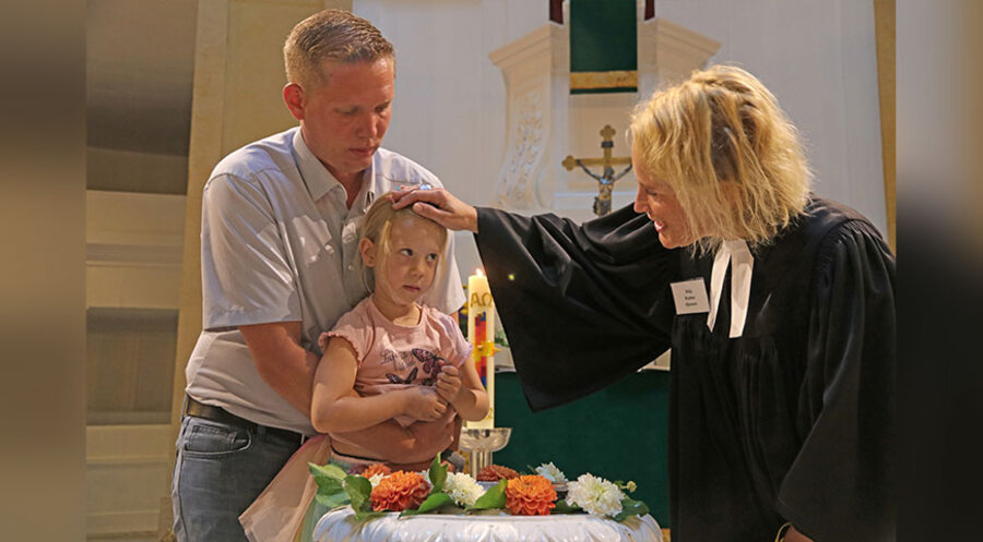 Pastorin Anja Kramer tauft die vierjährige Mara am 3. September in der Oldenburger St. Lambertikirche. Gehalten wird das Mädchen von ihrem Vater Inka Sander. Foto: epd-bild/Joerg Nielsen