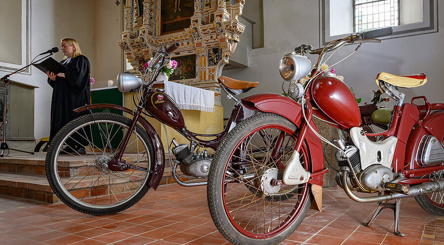 Pfarrerin Susanne Noack neben zwei Mopeds der Marke Simson. Foto: picture alliance/dpa | Patrick Pleul