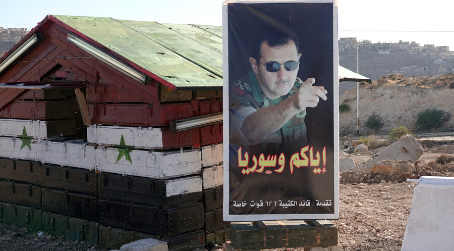 Zerstörtes Land: Ein Plakat von Baschar al-Assad steht vor einem ehemaligen Postenhäuschen in Syrien. Foto: picture alliance/dpa | Friedemann Kohler