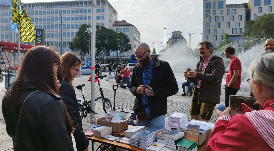 Christlicher Büchertisch am Karlsplatz in München mit Machete Maik. Foto: Alan Haufe