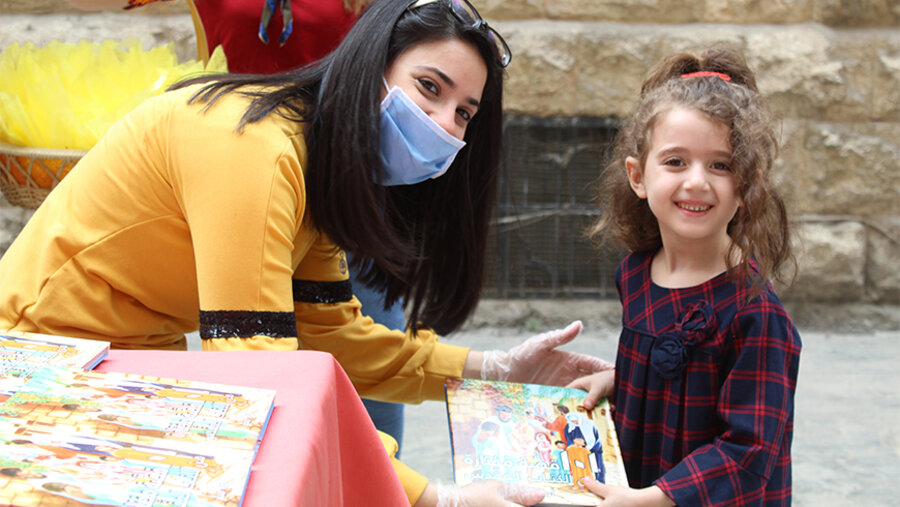 Eine Freiwillige verteilt zu Ostern christliche Bücher an Kinder. Foto: Syrische Bibelgesellschaft
