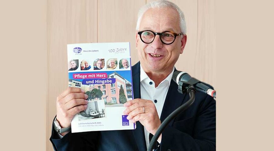 Der kaufmännische Vorstand der DGD Stiftung, Hubertus Jaeger, macht auf die 40-seitige Jubiläumsfestschrift aufmerksam. Foto: Birgit Schönig/DGD Stiftung