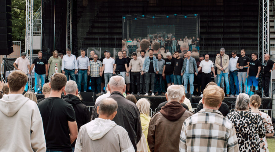 Pastoren und Älteste der Gemeinden Neuwied auf der Bühne im Gebet vereint. Foto: Simon David Zimpfer