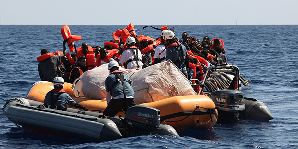 Mitglieder des „Sea Watch“-Teams verteilen im Mittelmeer Rettungswesten an Flüchtlinge. Foto: picture-alliance/JOKER