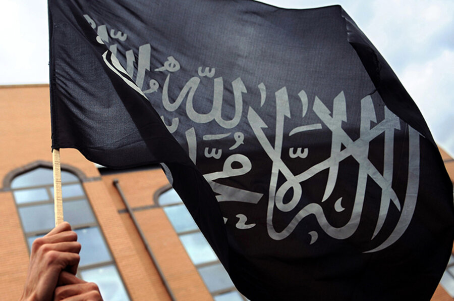 Ein Muslim hält eine islamische Fahne mit dem Glaubensbekenntnis, der sogenannten Schahada, in die Höhe. 