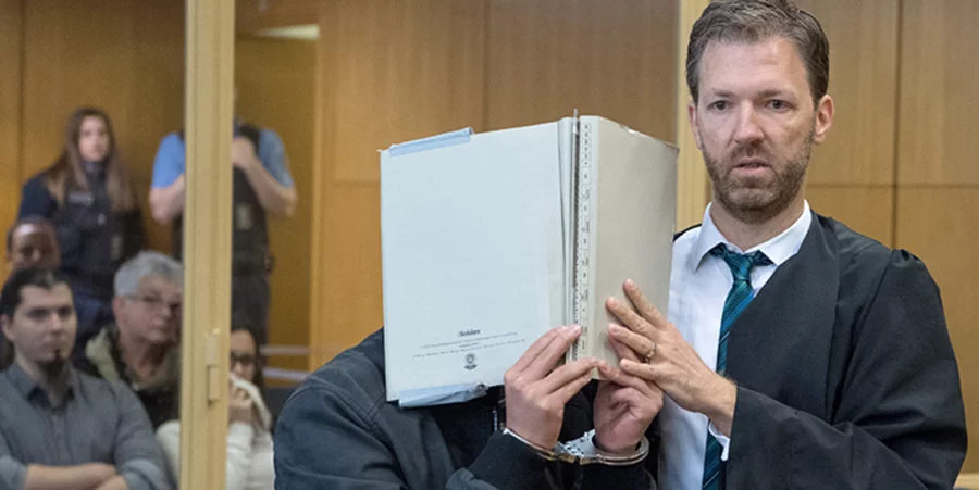 Rechtsanwalt Torsten Fuchs führt seinen Mandanten Yejun G. an den Zuschauern vorbei zur Anklagebank. Foto: picture-alliance/dpa