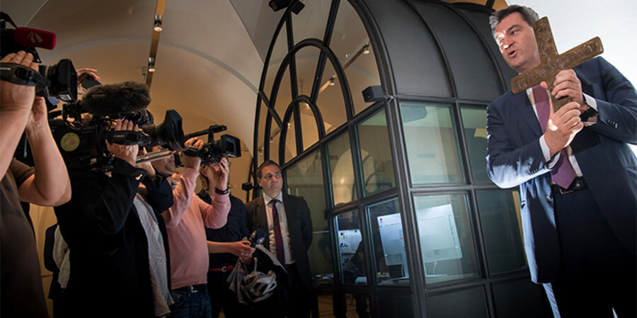 Der bayerische Ministerpräsident Markus Söder (CSU) hält am 24. April ein Kreuz, das er im Eingangsbereich der bayerischen Staatskanzlei anschließend aufhängt. Foto: picture-alliance/Peter Kneffel/dpa