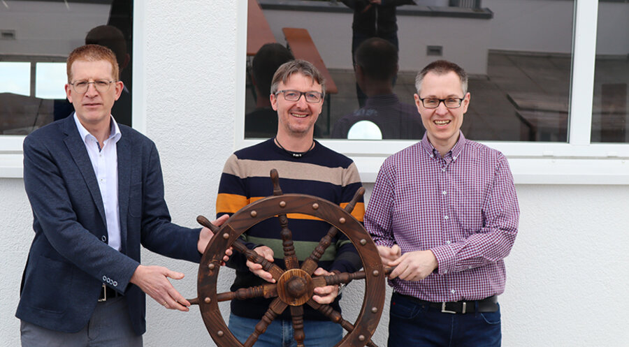 Nach erfolgreicher Arbeit übergibt Architekt Andreas Otte (Mitte) symbolisch das Steuerrad der MS Waterdelle an Hausleiter Schneider (rechts) und CVJM-Generalsekretär Hansjörg Kopp (links). Foto: CVJM Deutschland
